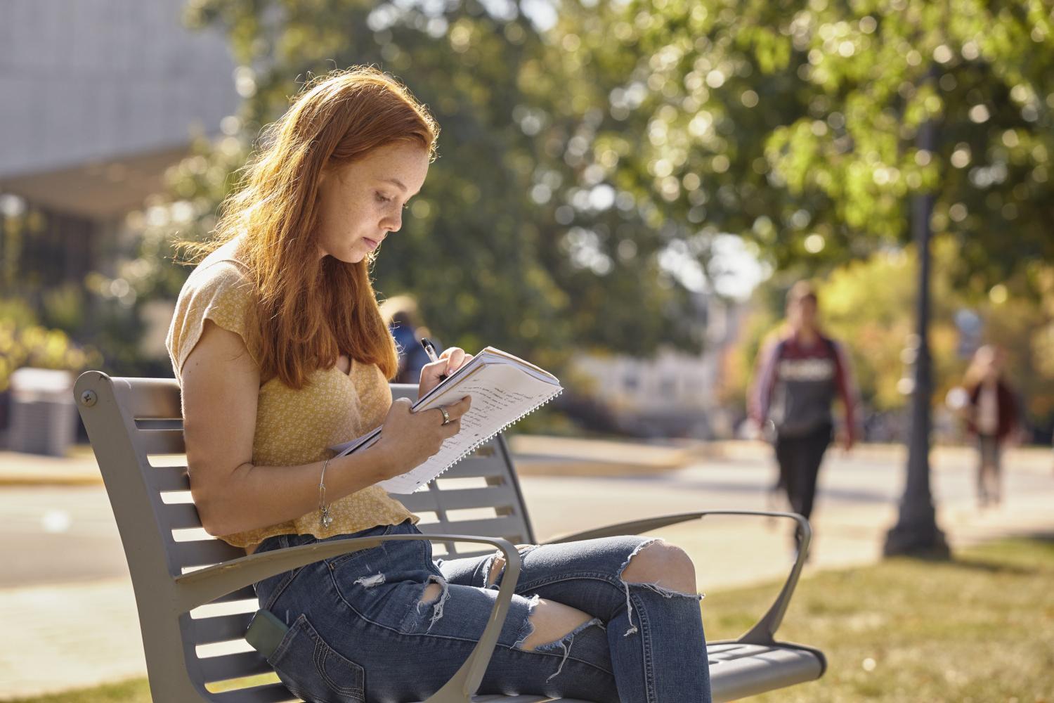 A <a href='http://ine1ty.bearinterestgroup.com'>全球十大赌钱排行app</a> student reads on a bench along Campus Drive.